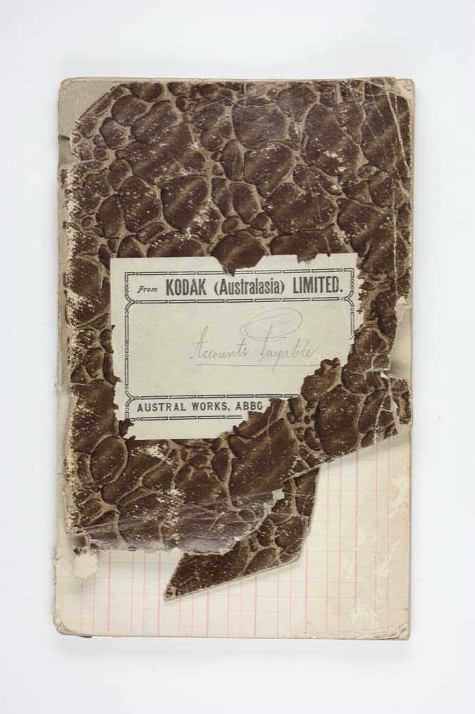 A worn early-20th-century accounts-payable ledger book, labeled 'From Kodak (Australasia) Limited'